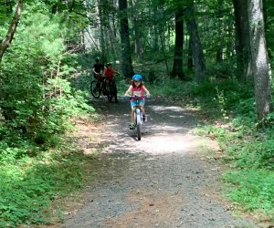 Camping near NYC: Child riding bike on a path through the woods at Dingmans Campground