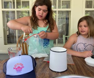 2 girls add ingredeints to make ice cream in a bag.