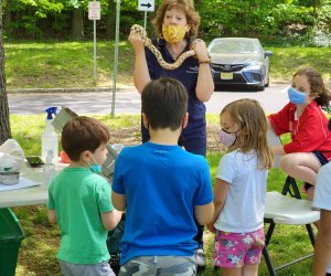 Masked kids looking at a women holding a snake